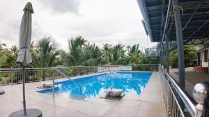 a swimming pool with an umbrella and palm trees at BIKI'S PALM VILLA in Kaduturutti