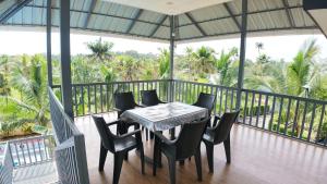a table and chairs on a balcony with palm trees at BIKI'S PALM VILLA in Kaduturutti