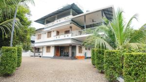 a large white building with trees in front of it at BIKI'S PALM VILLA in Kaduturutti