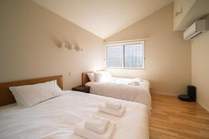 two beds in a room with white sheets and towels at Zekkei in Omachi