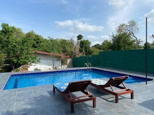a swimming pool with two chairs sitting next to it at Sigiri Nisala Resort in Sigiriya