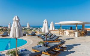 a swimming pool with lounge chairs and umbrellas at WellClub Resort - Suites & Wellness in Paphos