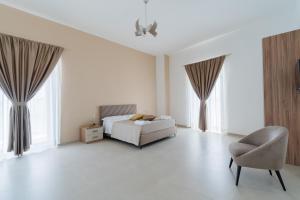 a white bedroom with a bed and a chair at Al Calico in Galatone