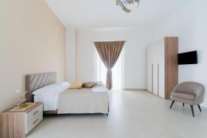 a white bedroom with a bed and a chair at Al Calico in Galatone