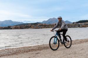 a man riding a bike on the beach at Tasman Holiday Parks - Wanaka in Wanaka