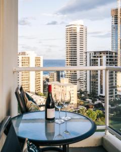 a wine bottle and two glasses on a table on a balcony at The Crest Apartments - Main Beach in Gold Coast