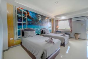 a bedroom with two beds and a painting on the wall at BCP Hotel in Ban Chang +25 photos