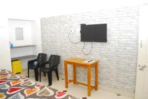 a room with chairs and a table and a tv on a brick wall at Olive inn in Kanyakumari
