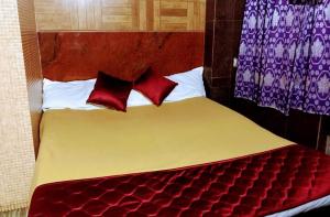 a bed with two red pillows on top of it at Olive inn in Kanyakumari
