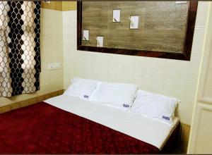 a bed with white sheets and pillows in a room at Olive inn in Kanyakumari