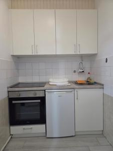a kitchen with white cabinets and a stove and a dishwasher at Garsonjera - centar Igalo in Igalo
