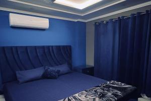 a blue bedroom with a bed and a blue wall at Bahria 777 Luxury Apartment in Lahore