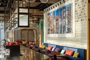 a restaurant with colorful chairs and a long bar at Wink Danang Riverside, Unscripted by Hyatt - 24 Hours stay in Danang