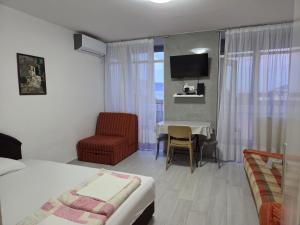 a bedroom with a bed and a table and a chair at Garsonjera - centar Igalo in Igalo
