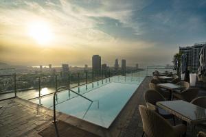 a swimming pool on the roof of a building with the sunset at Wink Danang Riverside, Unscripted by Hyatt - 24 Hours stay in Danang