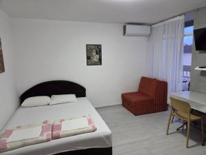 a bedroom with a bed and a table and a chair at Garsonjera - centar Igalo in Igalo