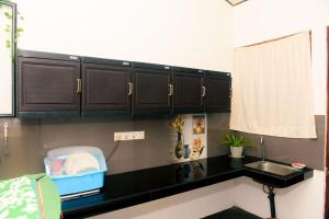 a kitchen with black cabinets and a sink at Bule Bells Villa in Matara