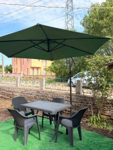 a picnic table and chairs with a green umbrella at Rapan Guesthouse in Bŭlgarevo