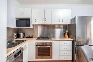 a kitchen with white cabinets and a stove top oven at 5-41 Park Street in Evans Head +7 photos