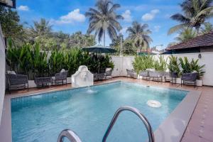 a swimming pool with chairs and an umbrella at FabHotel JM Residency in Mandrem