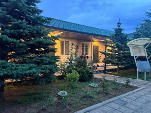 a yellow house with a tree and a yard at Guest house BIKA in Chon-Sary-Oy