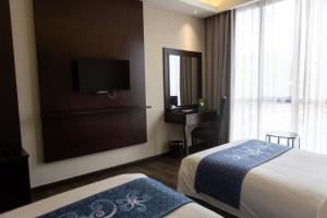 a hotel room with two beds and a television at Meritin Hotel in Kuching