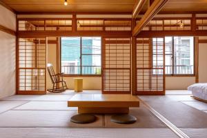 a room with a bed and a table and windows at 波と月 in Oarai