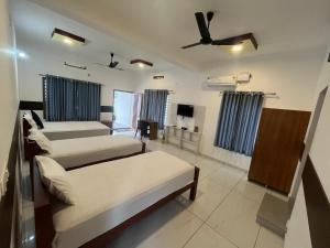 a bedroom with three beds and a ceiling fan at Romins Park in Kodanad