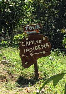a sign on a wooden post in the grass at Finca San Rafael - Cafe y Cacao in Minca