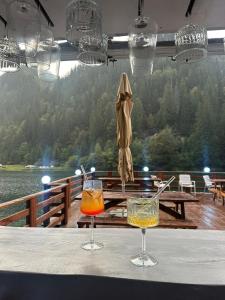 two glasses on a table with a view of a lake at CABANA MARIA-PETRIMANU in Ciungetu