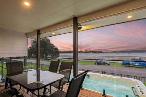 a dining room with a table and a large window at Marea at Tanilba Bay in Lemon Tree Passage