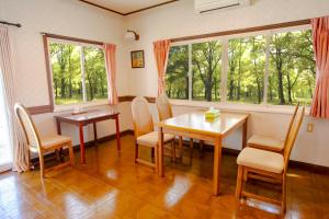 a dining room with a table and chairs and windows at Pension Serenade in Hakuba