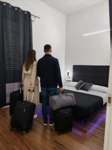 a man and woman standing in a bedroom with their luggage at Relax Rooms in Trapani +7 photos