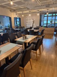 a restaurant with wooden tables and chairs and windows at Hotel Corsten - Home of Lukes Steaks & More - Heinsberg in Heinsberg