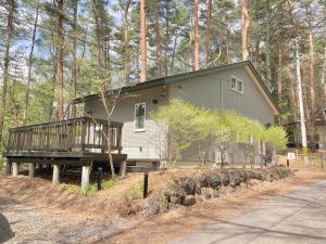 a house with a porch and a deck in the woods at Villa Mon Petit Nid Komoro in Komoro