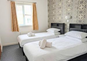 three beds in a room with white sheets and pillows at The Mayfair in Skegness
