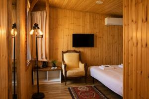 a bedroom with a bed and a chair and a television at Winery & Brewery - Family Guesthouse "Villa Rbona" in Khashuri