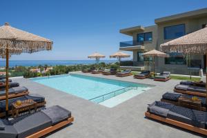a villa with a swimming pool with chairs and umbrellas at Infinite View Villa in Platanias