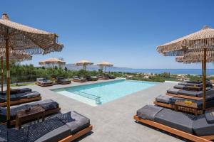 a resort with a pool with lounge chairs and umbrellas at Infinite View Villa in Platanias