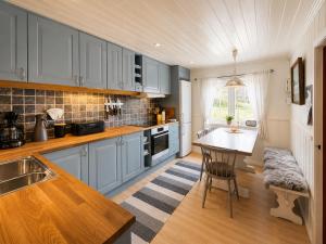 a kitchen with blue cabinets and a table in it at Hallingstue by Hallstensgaard - Geilo in Geilo