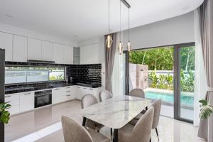 a kitchen with white cabinets and a table and chairs at Harmony Pool Villa Ao Nang in Ao Nang 