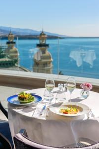 a table with two plates of food and wine glasses at Hôtel de Paris Monte-Carlo in Monte Carlo +42 photos