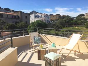 a patio with two chairs and a table on a balcony at Résidence San Pancraziu in LʼÎle-Rousse