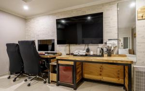 a room with a desk with two chairs and a television at Cats Hotel in Puch'ŏn-yŏk