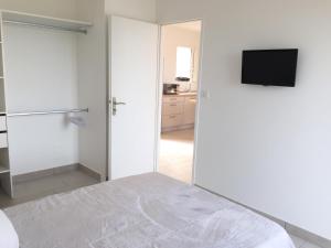 Habitación blanca con cama y TV en Résidence San Pancraziu en LʼÎle-Rousse