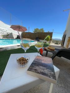 a table with two glasses and a book on it at Casa Cueva Sol con chimenea y piscina privada in Pozo Alcón