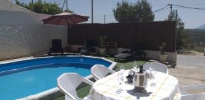 a table and chairs next to a swimming pool at Casa Cueva Sol con chimenea y piscina privada in Pozo Alcón