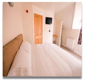 a white bed in a room with a television at The Queens Head in Llanidloes