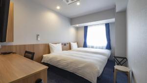 a room with two beds and a desk and a window at Toyoko Inn Kitakami-eki Nishi-guchi in Kitakami