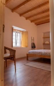 a bedroom with a bed and a chair and a window at um pouco de campo in Torres Vedras